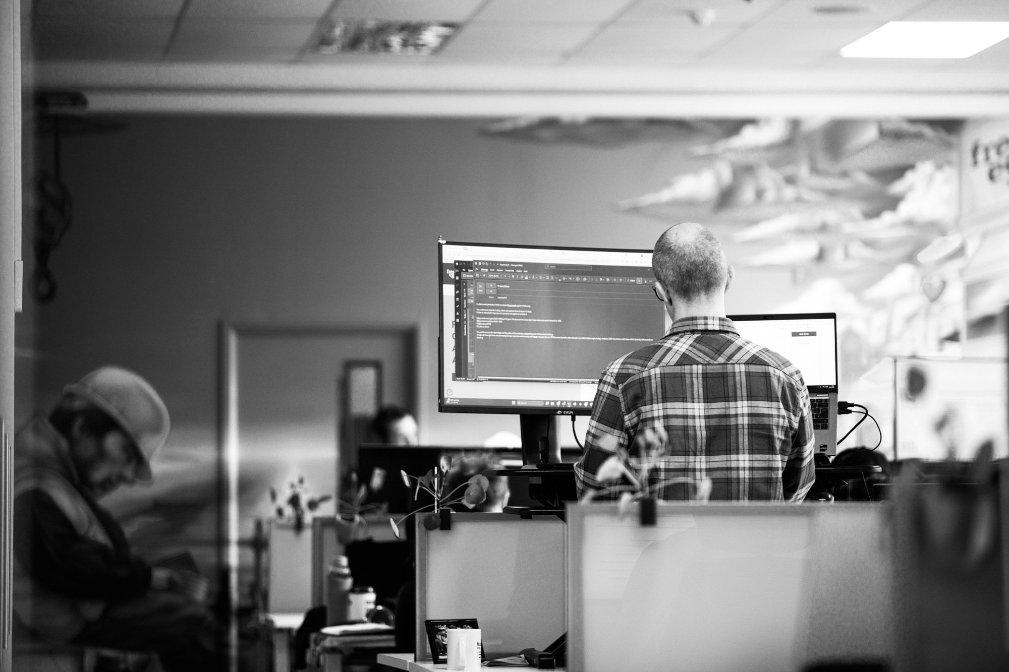 Developer working at standing desk with multiple monitors in modern office environment