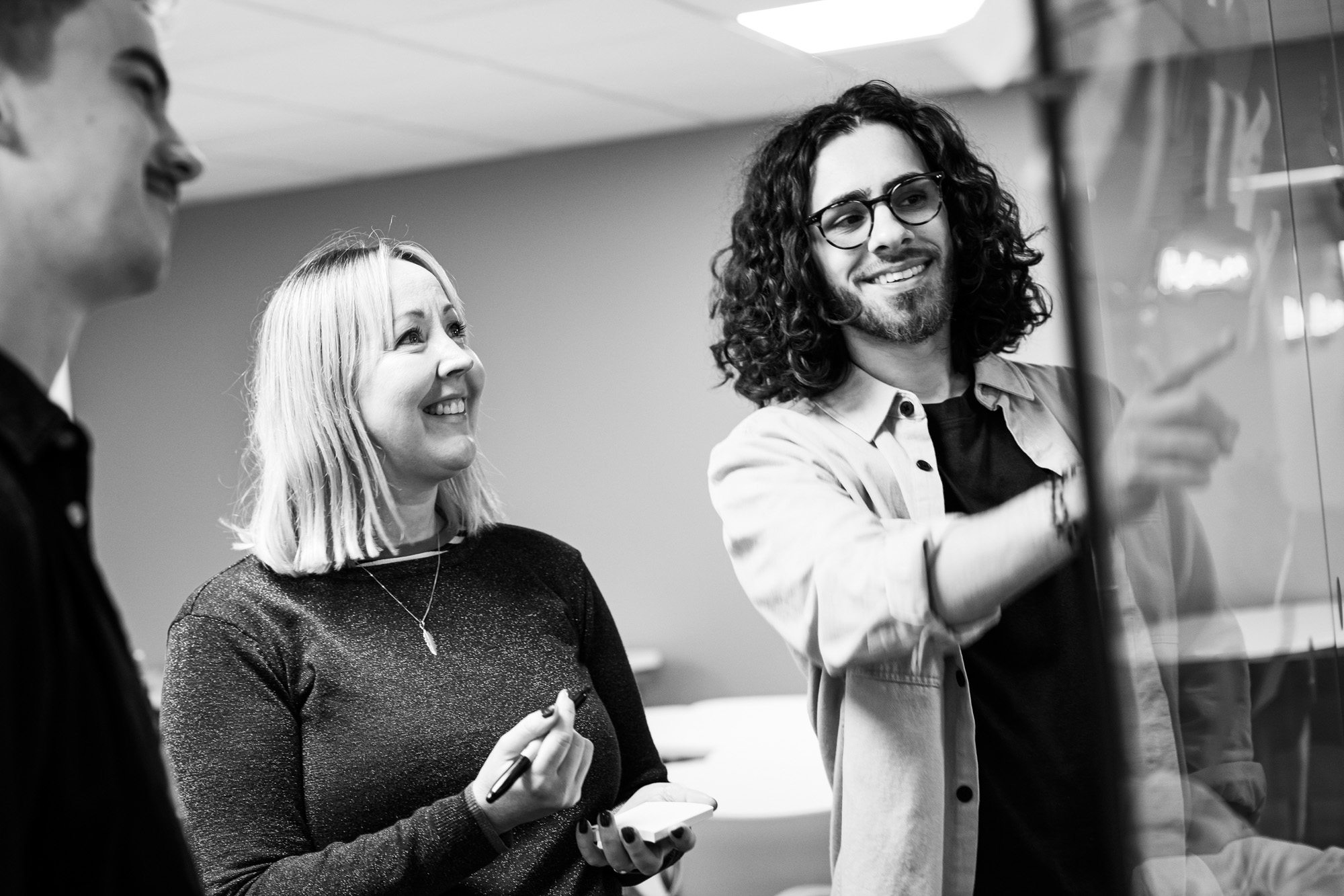Two smiling professionals in business casual attire having a conversation in a modern office setting
