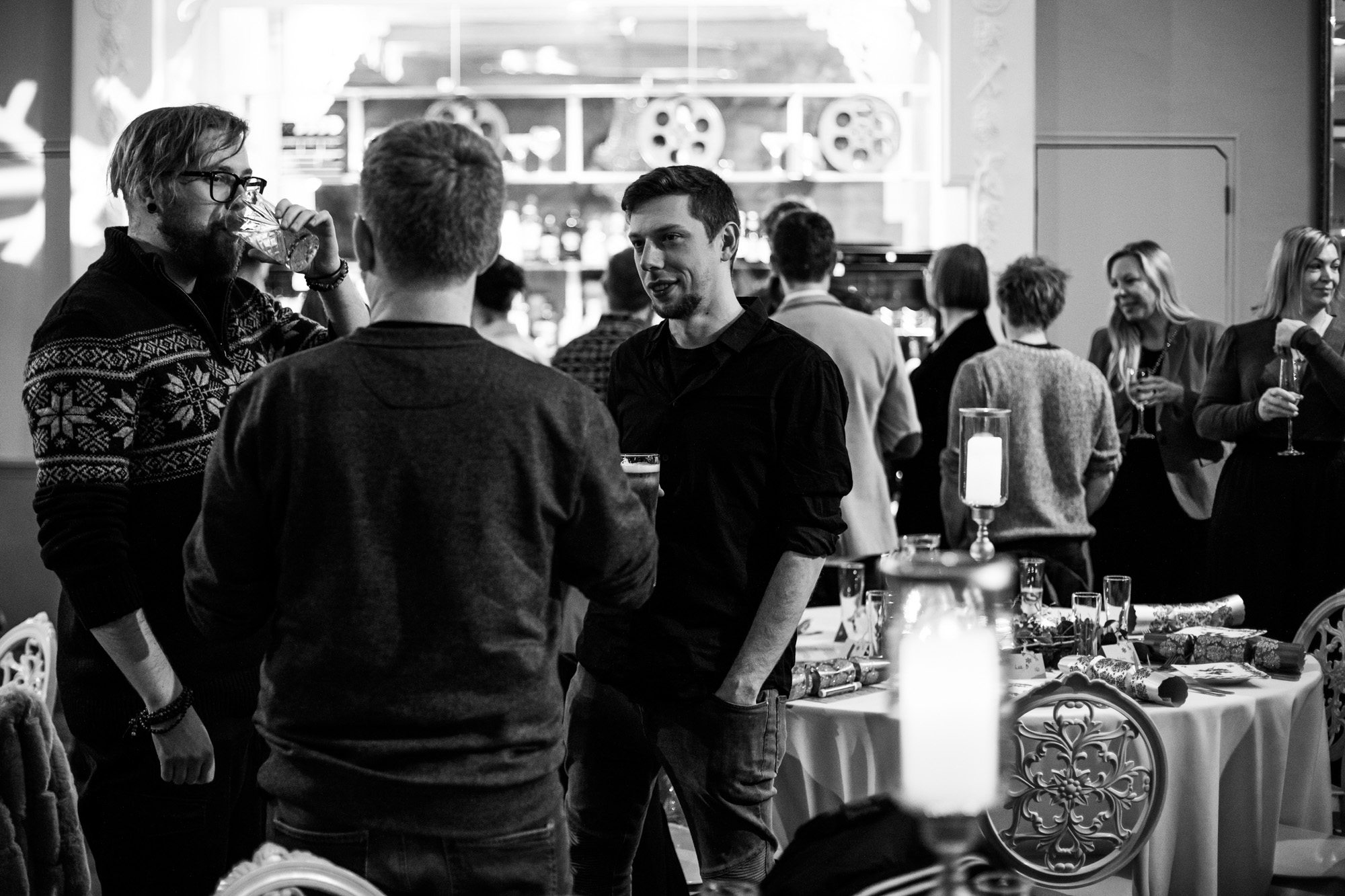 People networking at a casual indoor business event with drinks and refreshments in black and white