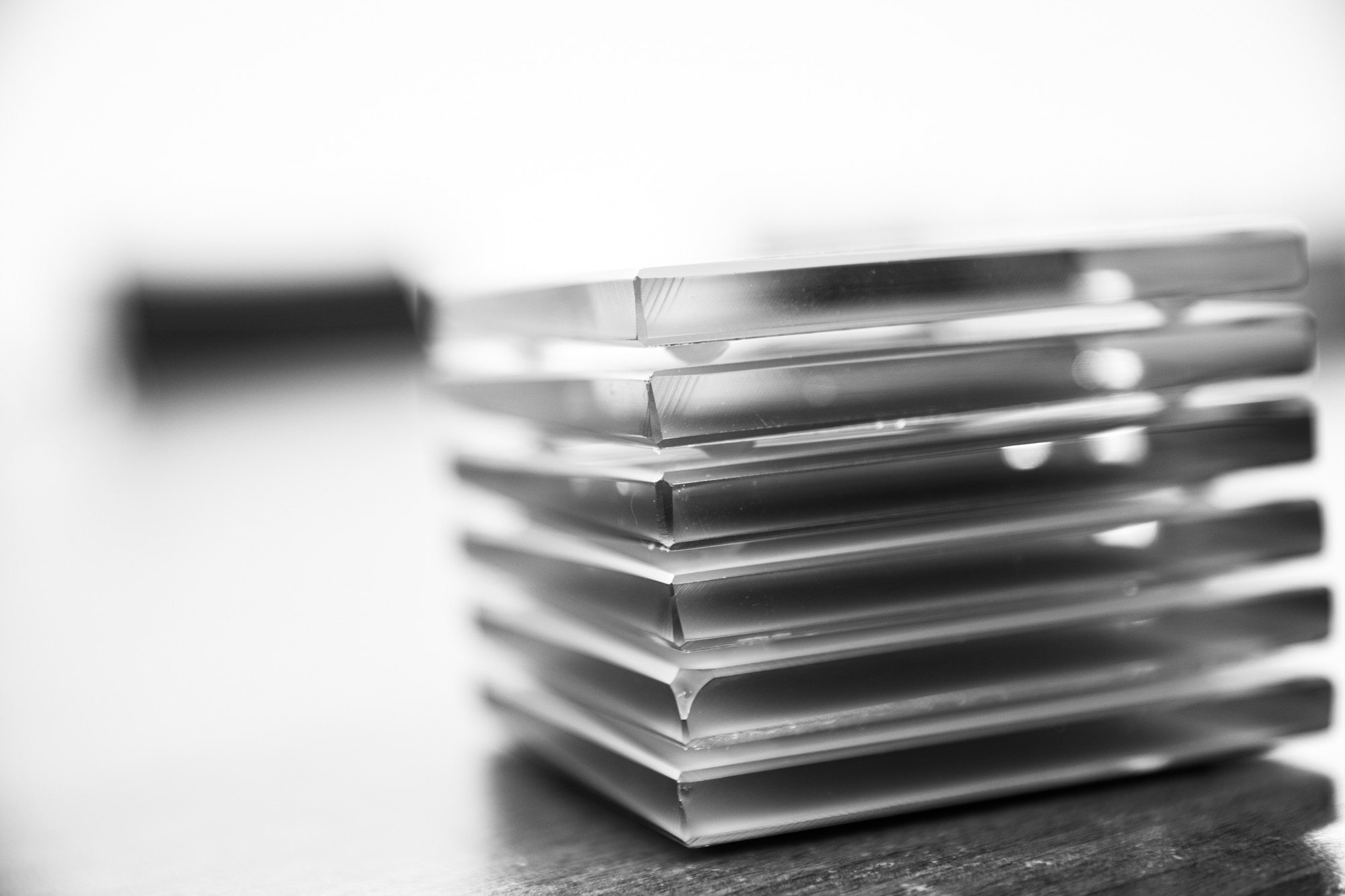 Stack of books in black and white with blurred pen in background on wooden surface