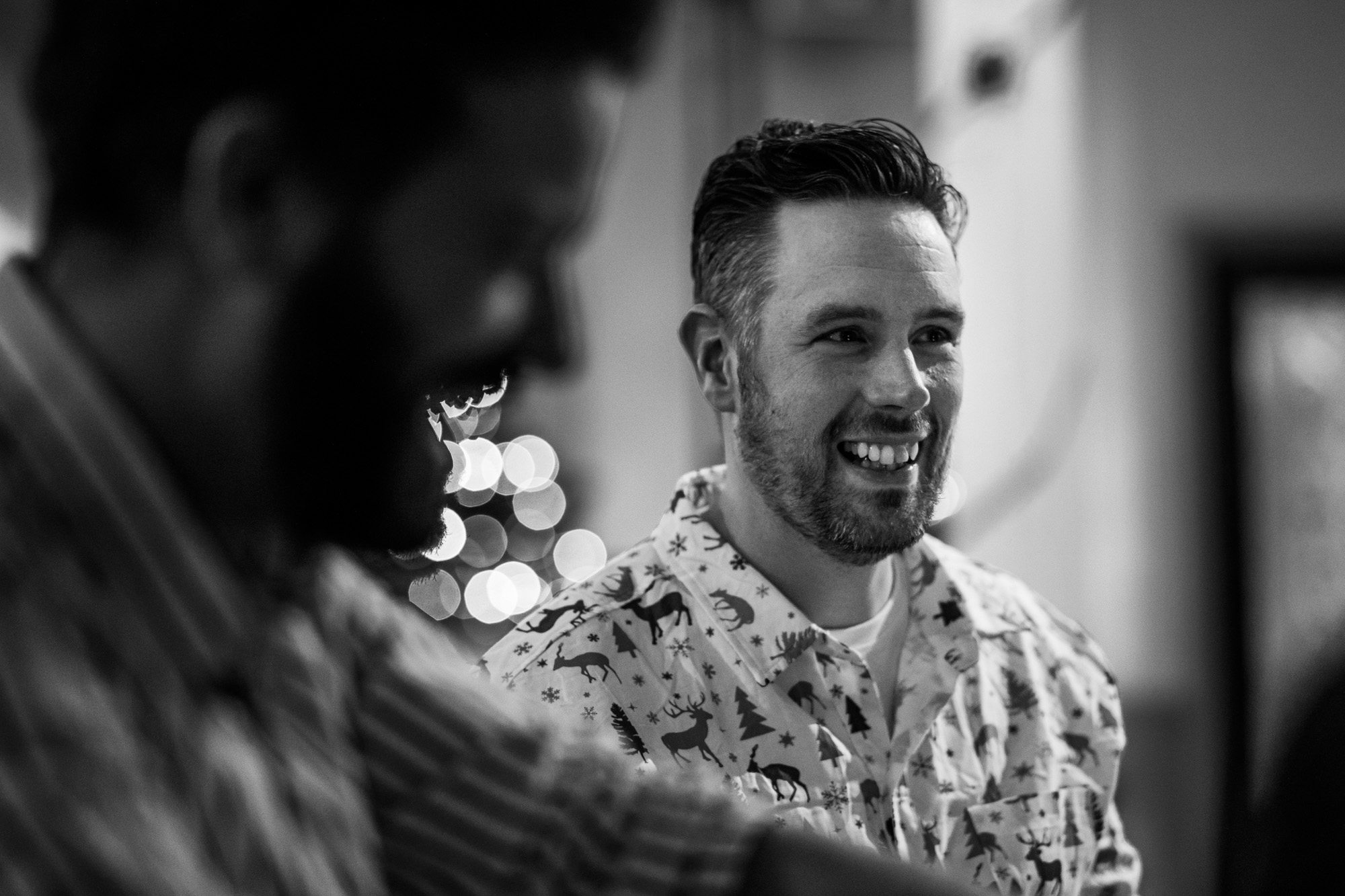 Man in patterned shirt smiling in black and white lifestyle photograph with bokeh lighting effects