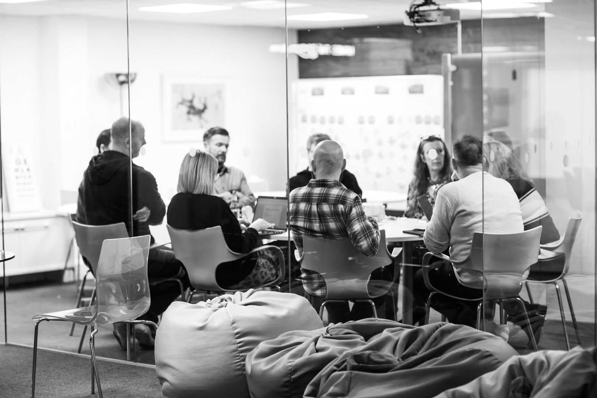 Business team meeting in modern glass conference room with presentation screen in background