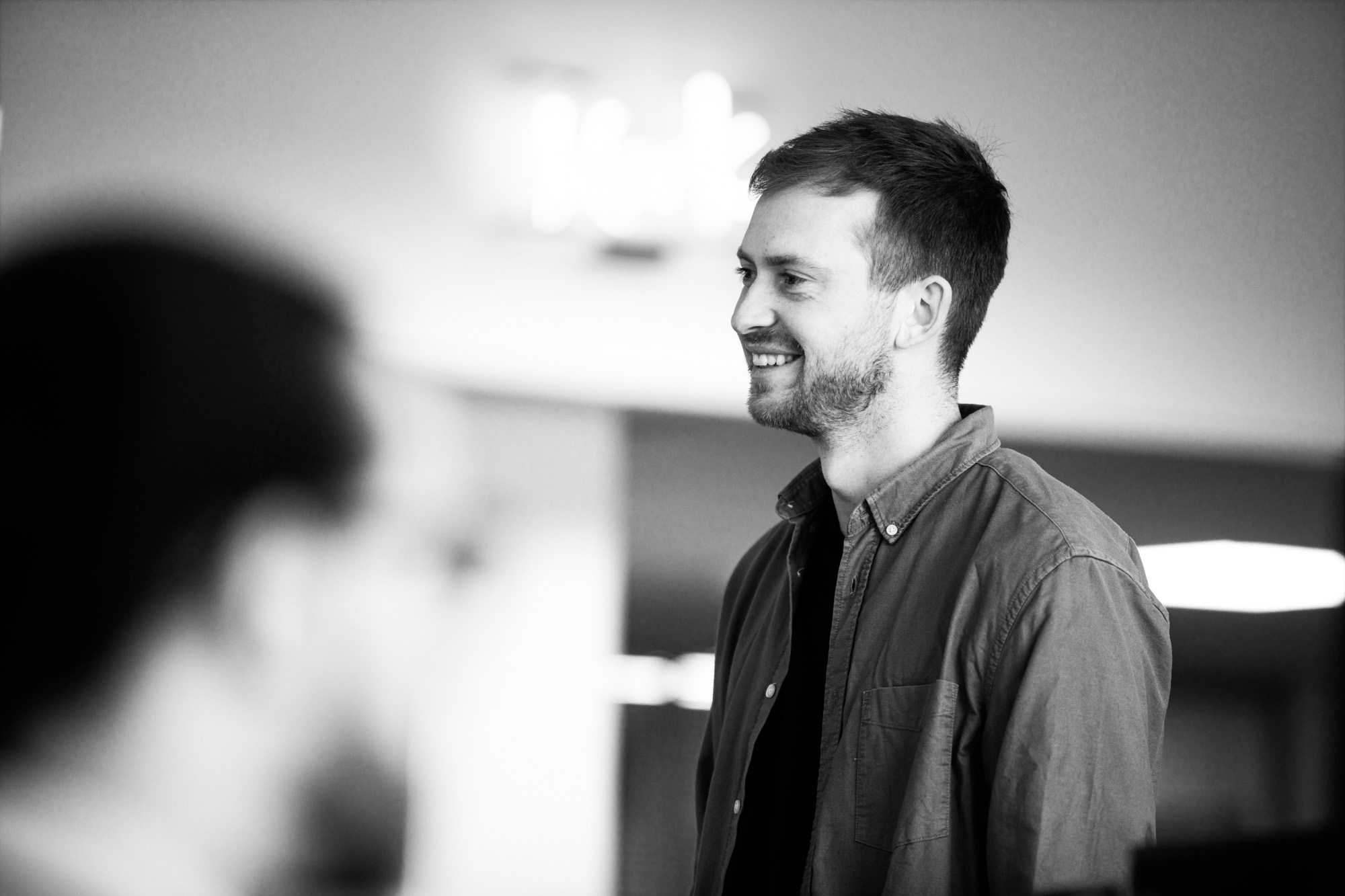 Smiling man in button-down shirt looking to the side in black and white professional portrait