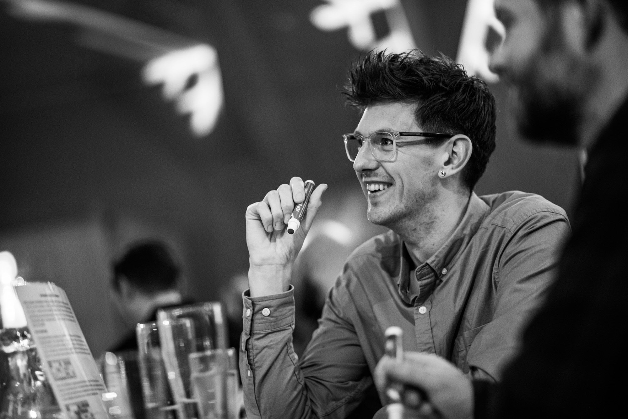 Young professional man with glasses smiling while holding pen in black and white office setting