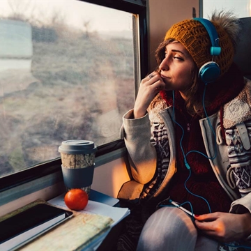 A Photo of a Women Sitting on The Train Looking Out The Window